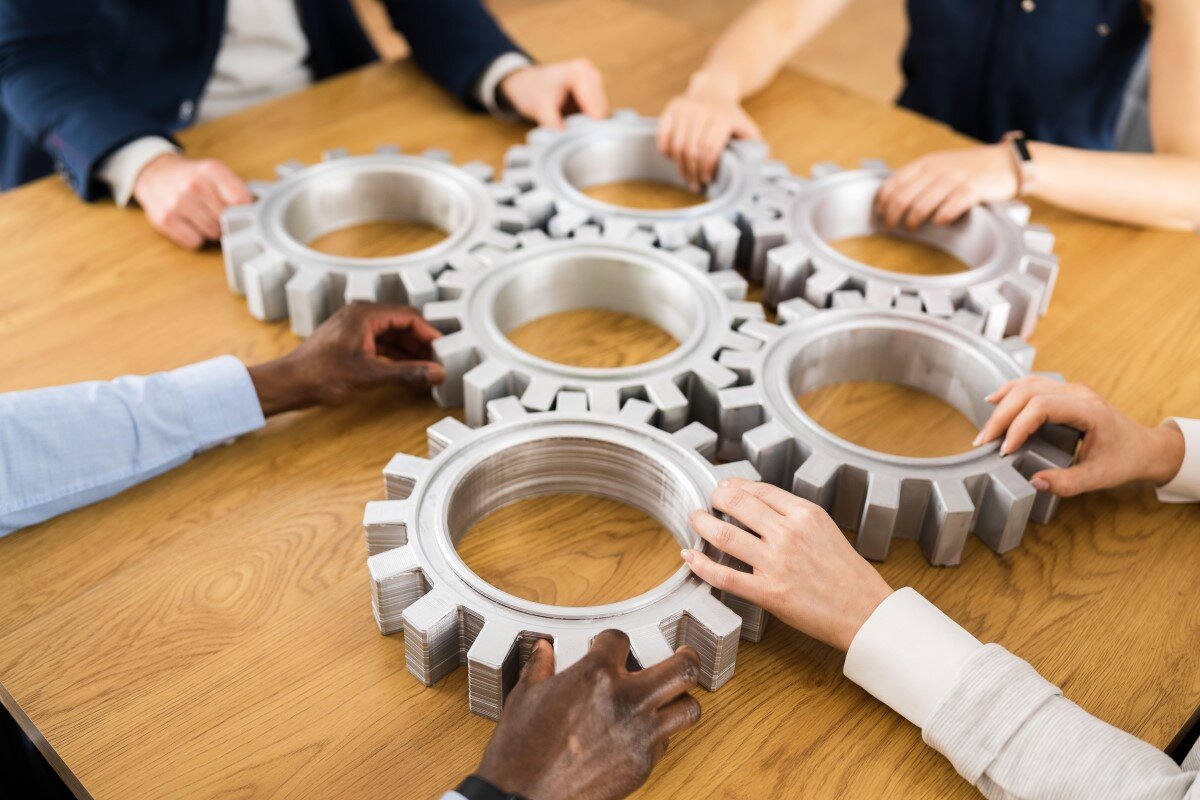 Businesspeople Hands Joining Gears. Support And Implementation | © Andriy Popov / Alamy 